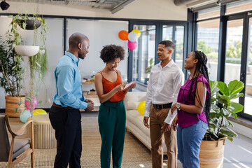 Colleagues in office discussing project, smiling and engaging in conversation
