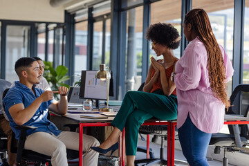 In office, diverse colleagues discussing project, smiling and engaging enthusiastically