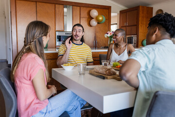 Friends enjoying conversation and snacks at home around dining table