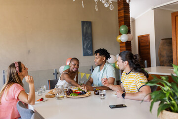 Friends enjoying conversation and sharing snacks at home during casual gathering
