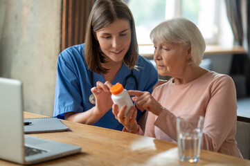 Nurse explaining senior woman patient medications in medical clinic or in hospice care