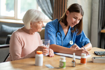 Woman providing health care and assistance to aged patient offering treatment and medication