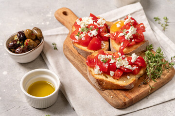 Freshly prepared bruschetta with  tomatoes, feta cheese, and herbs, served on a wooden cutting board 