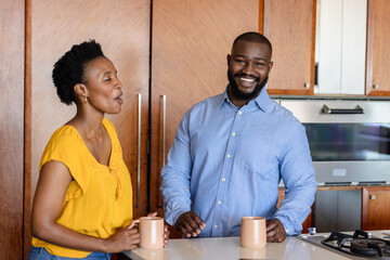 Couple enjoying coffee and conversation in modern kitchen, smiling together
