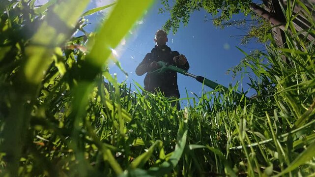 A man mowing grass in his yard with a trimmer
