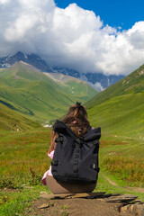 Fototapeta premium Female tourist with backpack enjoying stunning mountain landscape in the caucasus region, connecting with nature's beauty and finding tranquility in the vastness of the panorama. Vertical photo