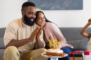 Celebrating birthday, happy couple clapping with cake and gifts on table