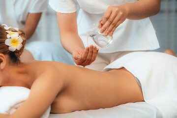 Masseur hands pouring aroma oil on couple's back. Masseuse prepare oil massage procedure for customer at spa salon in luxury resort. Aroma oil body massage therapy concept. Quiescent
