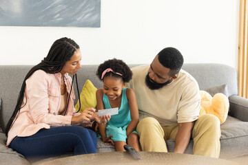 Family enjoying quality time together on couch, smiling and looking at photo