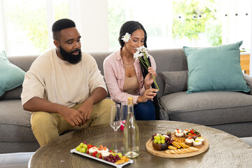 At home, African American couple with snacks and flowers, feeling relaxed together