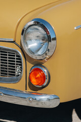 Round Headlight and Chrome Bumper of Yellow Classic Car – Close-Up