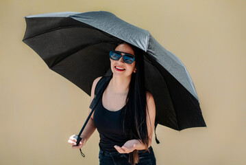 Fototapeta premium Happy woman smiling under a black umbrella on sunny day