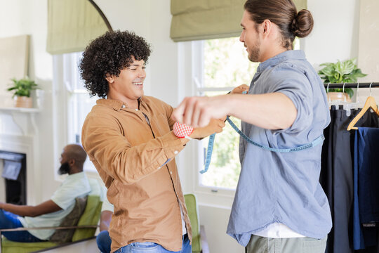 Friends measuring suit size, preparing for wedding, smiling and enjoying moment - Powered by Adobe