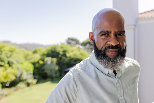 African American man standing outdoors, looking thoughtful in sunny garden setting