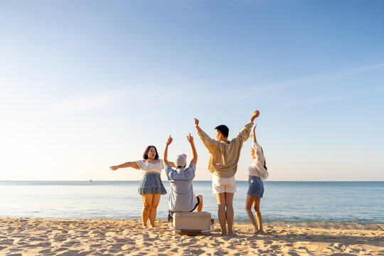 Happy Asian man and woman travel the sea on summer beach holiday vacation. Group of People friends enjoy and fun outdoor lifestyle holding cooler box walking to picnic on tropical beach in sunny day. - Powered by Adobe