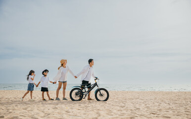 Obraz premium Parents and children walking on the sandy beach pushing bicycles a family scene filled with smiles happiness and the carefree enjoyment of a day under the sun. Family on beach vacation