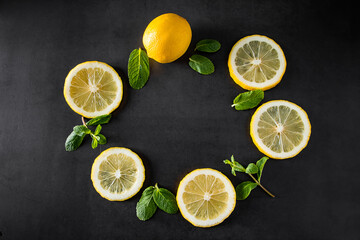 Fresh juicy lemon slices on black background. Cocktail ingredient - mint leaves and lemon. Food...