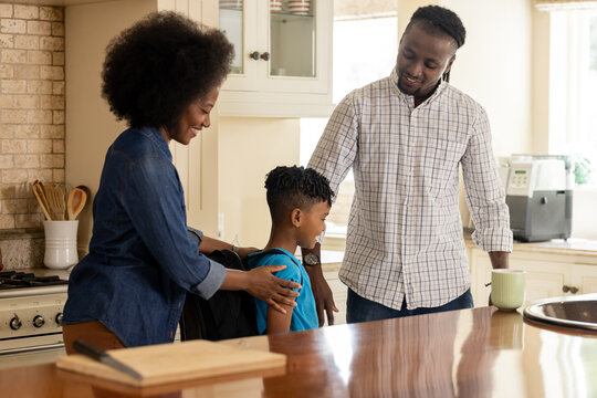 In kitchen, parents supporting child preparing for school with smiles and encouragement