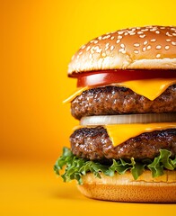Delicious double cheeseburger with melted cheese, fresh lettuce, tomato, and a sesame seed bun against a vibrant yellow background. Perfect for food photography or advertising.