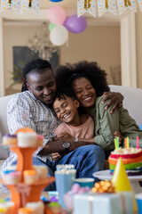 African American family celebrating birthday at home, smiling and embracing joyfully