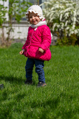 Fototapeta premium A young girl's outdoor exploration: Spring attire, joy, and verdant backdrop