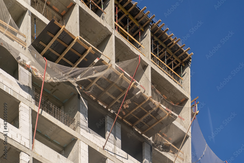 Aufkleber modern building construction: a multi-story structure with concrete and safety netting against a viv
