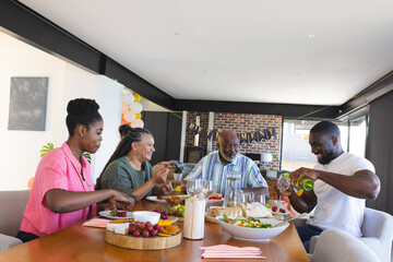 Family enjoying festive meal together, sharing laughter and pouring drinks at home