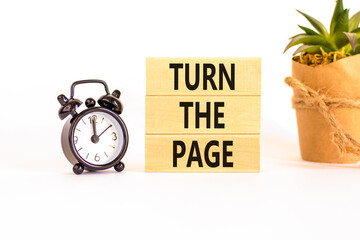Turn the page symbol. Concept words Turn the page on beautiful wooden block. Black alarm clock....