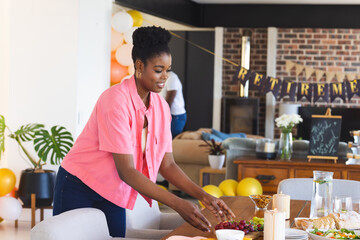 Woman arranging table for retirement party at home, preparing festive decorations