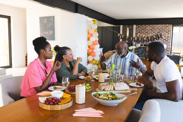 Family enjoying retirement celebration with food and drinks at home, sharing stories