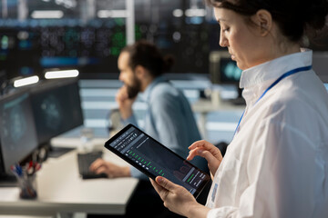 Close up of engineer using tablet in data center, managing server virtualization, running scripts....