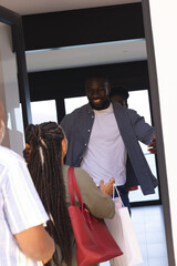 Obraz premium Man welcoming guests at home, smiling and holding gift bags at doorway