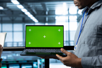 Employees in data center using isolated screen mockup laptop, integrating green technologies. IT experts in server room using chroma key notebook to implement sustainable energy solutions