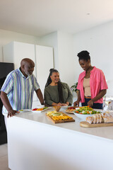 Family preparing delicious meal together in modern kitchen, sharing joyful moments