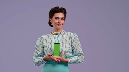 Young woman in vintage outfit and with glamorous hairstyle poses on purple studio background.