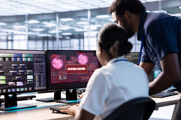 African american engineer in server hub helped by manager to investigate breach alerts, working to...