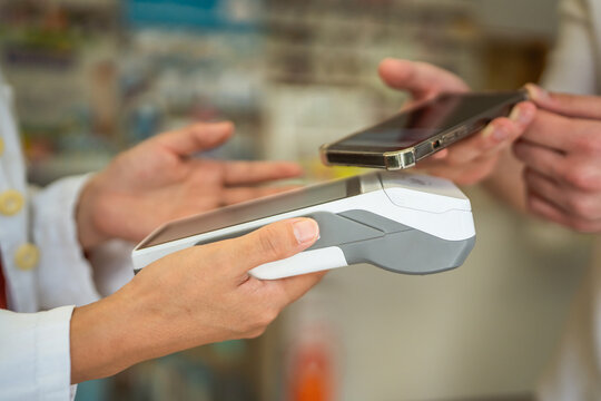 young man paying by credit card near pharmacist with payment terminal