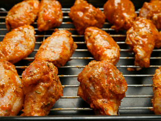 Cooking fresh chicken wings on an oven. The product is covered in red Asian style sauce and ready for cooking in high temperature. Party finger snack food.