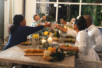 Family celebrating with dinner, raising glasses in joyful toast at home