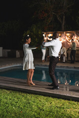 Obraz premium Senior couple dancing joyfully by poolside during evening celebration outdoors