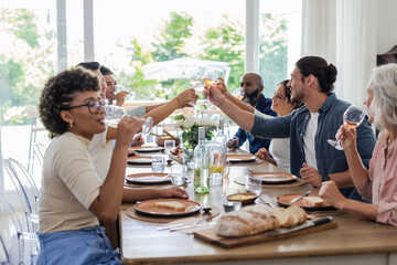 Friends and family toasting with wine glasses at elegant dining table celebration