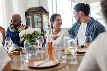 At wedding reception, friends laughing and talking with drinks and flowers around
