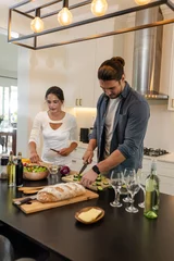 Selbstklebende Fototapeten Couple preparing fresh salad and bread in modern kitchen, enjoying cooking together © wavebreak3
