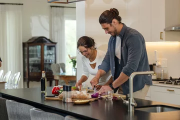 Selbstklebende Fototapeten Couple preparing meal together in modern kitchen, smiling and enjoying cooking © WavebreakMediaMicro