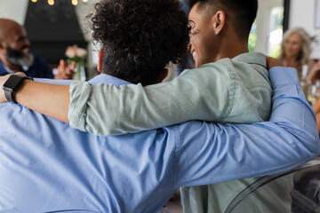 Friends embracing warmly at wedding reception, celebrating joyful moments together