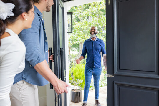 Welcoming guest at home, smiling couple greeting friend at front door - Powered by Adobe