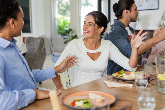 Guests enjoying lively conversation and delicious meal at wedding reception table
