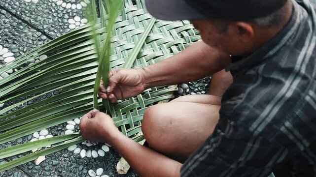 A Skilled Indonesian Craftsman is Expertly Weaving Palm Leaves into Beautiful Baskets with Care