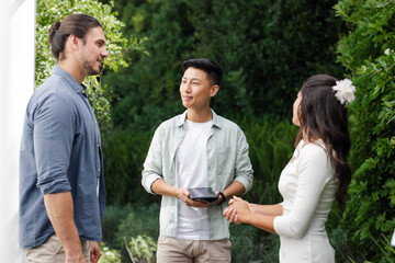 Celebrating wedding, friends conversing outdoors surrounded by lush greenery