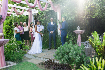 Bride and groom exchanging vows outdoors surrounded by family and friends